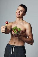 vrolijk Mens met naakt gespierd torso bord salade gezond voedsel vegetarisch foto