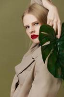 glamoureus vrouw in jas rood lippen mode palm blad levensstijl poseren foto