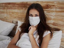 vrouw in medisch masker leugens in bed in quarantaine pandemisch coronavirus ziekte infectie foto