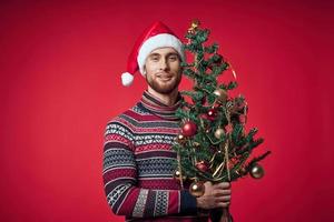 Mens in Kerstmis kleren Kerstmis boom decoratie vakantie rood achtergrond foto
