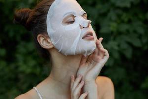 mooi hoor vrouw wit masker houdt zijn hand- in de buurt zijn gezicht dermatologie bladeren in de achtergrond foto