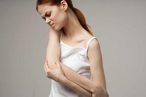 vrouw in wit t-shirt reuma elleboog pijn Gezondheid problemen licht achtergrond foto