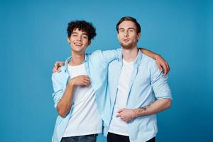 jong mannen in blauw overhemden knuffelen Aan geïsoleerd achtergrond vrienden pret foto