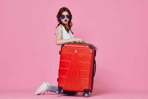 vrolijk vrouw met rood koffer reizen roze achtergrond vlucht foto