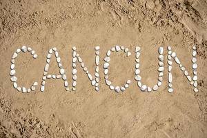 Cancun - woord gemaakt met stenen Aan zand foto