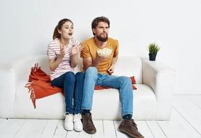 Mens en vrouw aan het kijken films binnenshuis met popcorn en bloem in een pot foto