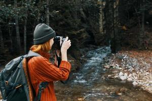 vrouw met een camera Aan natuur in de bergen in de buurt de rivier- kant visie foto