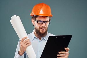Mens arbeider met documenten in handen vervelend bril oranje helm veiligheid professioneel foto