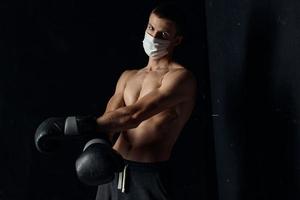 portret van een bokser in een medisch masker en zwart handschoenen Aan een geïsoleerd achtergrond foto