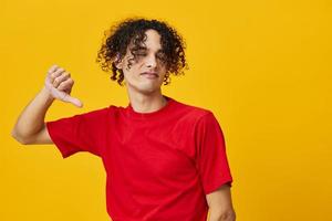 ontevreden grappig Kaukasisch jong Mens in rood t-shirt tonen dis Leuk vinden gebaar poseren geïsoleerd Aan geel studio achtergrond. de het beste aanbod met vrij plaats voor reclame. emoties voor elke dag concept foto