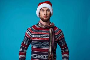 knap Mens in een de kerstman hoed met een telefoon in zijn handen blauw achtergrond foto