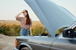 vrouw verdrietig en boos over auto afbreken Aan weg reis alleen en zetten haar handen Aan haar hoofd van niet begrip, auto probleem foto