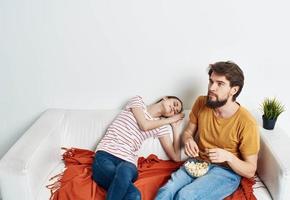 een vrouw is resting Aan de bankstel en een Mens met een popcorn bloem in een rood plaid pot foto