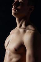 sexy bodybuilder met naakt torso Aan zwart achtergrond portret kant visie foto