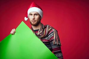 knap Mens in een de kerstman hoed Holding een banier vakantie rood achtergrond foto