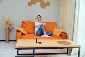 vrouw Bij huis Aan oranje sofa telefoon Aan tafel en vapen foto