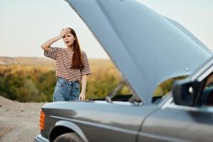 vrouw verdrietig en boos over auto afbreken Aan weg reis alleen en zetten haar handen Aan haar hoofd van niet begrip, auto probleem foto