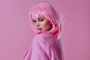 portret van een charmant dame roze jasje Holding haar- schoonheidsmiddelen kleur achtergrond ongewijzigd foto