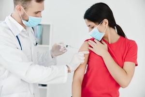 mannetje dokter maakt een injectie in de arm van een geduldig covid vaccinatie foto