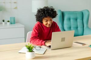 Afrikaanse Amerikaans meisje gebruik makend van laptop computer hebben video babbelen Bij huis. jong vrouw hebben virtueel vergadering online babbelen video telefoontje conferentie. werk aan het leren van huis, afgelegen docent. foto