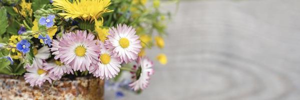 een boeket wilde bloemen van vergeet-mij-nietjes, madeliefjes en gele paardebloemen in volle bloei in een rustieke pot foto