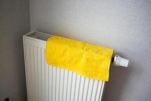 geel kleur handdoek drogen Aan verwarming radiator, foto