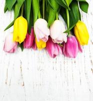 boeket van roze en gele tulpen op een houten achtergrond foto