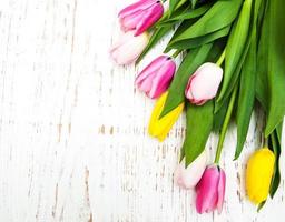 boeket van roze en gele tulpen op een houten achtergrond foto