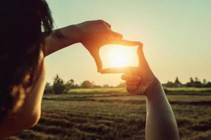 vrouw hand- framing visie ver weg over- zonsondergang. bedrijf concept foto