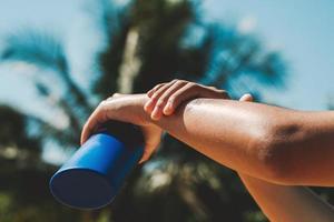 dichtbij omhoog jong vrouw toepassen zonnescherm lotion Aan hand- met blauw lucht achtergrond foto