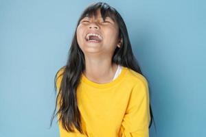 schattig weinig meisje lach gelukkig Aan blauw achtergrond foto