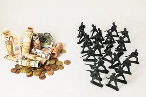 oorlog concept met geld en miniatuur soldaten foto