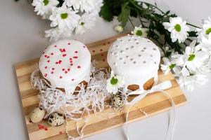 twee Pasen taarten staan Aan een houten bord met kwartel eieren en wit bloemen foto