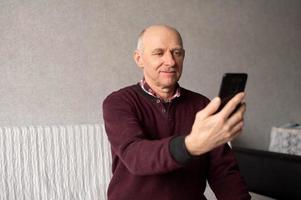 een volwassen Mens duurt een selfie Aan zijn telefoon in de leven kamer foto