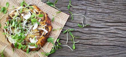 zelfgemaakte vegetarische pizza met zonnebloem spruiten op een houten tafel achtergrond foto