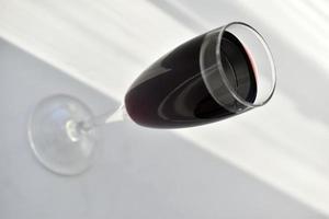 klein glas rode wijn op een witte achtergrond met schaduwen