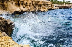 Egypte, 2021 - Opspattende golven die tegen de rotsen beuken op het strand van de Rode Zee