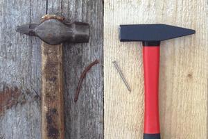 oud hamer, roestig nagel vs merk nieuw hamer en nieuw glimmend nagel Aan houten borden foto