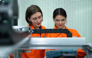 beide van vrouw in een elektronisch onderdelen fabriek gebruik makend van een productie lijn controleur en zijn aanbevelen collega's naar gebruik deze hulpmiddel. foto