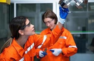 in een elektronisch onderdelen faciliteit, twee vrouw ingenieurs in de plant, inspecteren en testen robot handen gebruikt in de productie van elektronisch componenten. foto