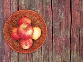 rode appels op een rieten plaat op een houten tafel achtergrond