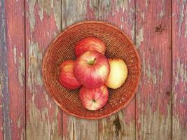 rode appels op een rieten plaat op een houten tafel achtergrond