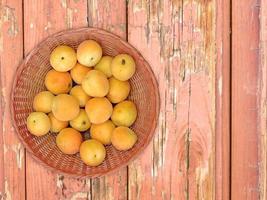 abrikozen in een rieten kom op een houten tafel achtergrond foto