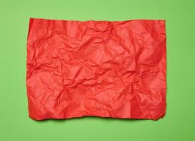 verfrommeld rechthoekig vel van rood papier Aan een groen achtergrond, top visie. plaats voor opschrift foto