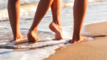 twee mensen lopen met blote voeten op zand foto