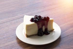 bosbessenroom cheesecake op een witte plaat op een houten tafel foto