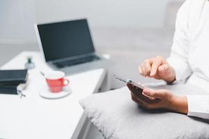 sociaal media dag concept. vrouw freelancer beginnend werken dag vroeg in leven kamer voor website met smartphone. zakenvrouw werken in huis kantoor. vrouw communiceren met online technologie. foto