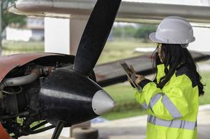 technicus die de motor van het vliegtuig repareert, vrouwelijke lucht- en ruimtevaarttechniek die vliegtuigmotoren controleert, aziatisch monteur onderhoud inspecteert vliegtuigmotor; foto