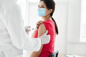 dokter Holding een injectiespuit geïnjecteerd in de schouder van een vrouw geduldig covid vaccinatie foto