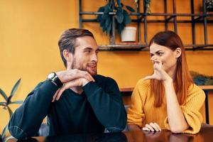 vrolijk Mens en vrouw gebaren met hun handen en zittend Bij een tafel in een cafe communicatie vrienden een kop van koffie foto